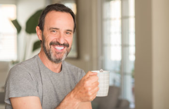 mature smiling man holding a coffee cup and smiling, 