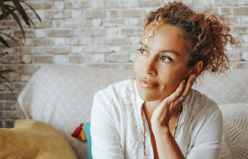 pensive woman in tight curly hair sitting on the couch, 